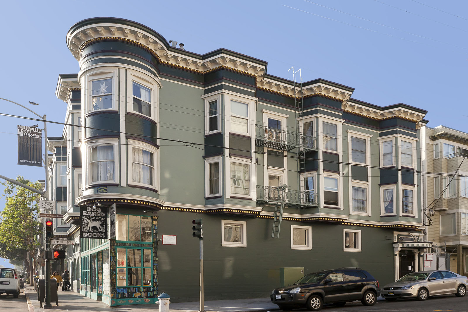 A street view of a green building with a black car parked in front.