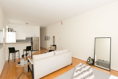 A white couch sits in a living room with a dining table and chairs.