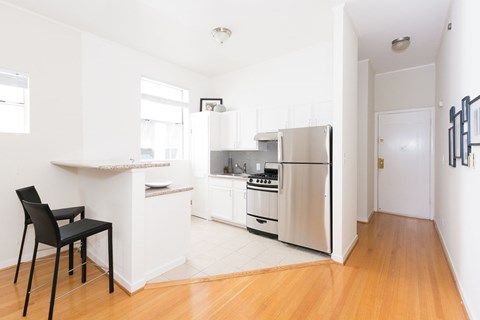 A kitchen with a black chair and white cabinets.