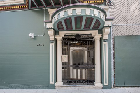 A green building with a white door and a sign that says 3605.