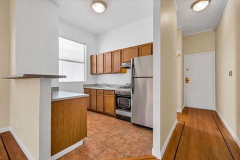 A kitchen with wooden cabinets and a tile floor.