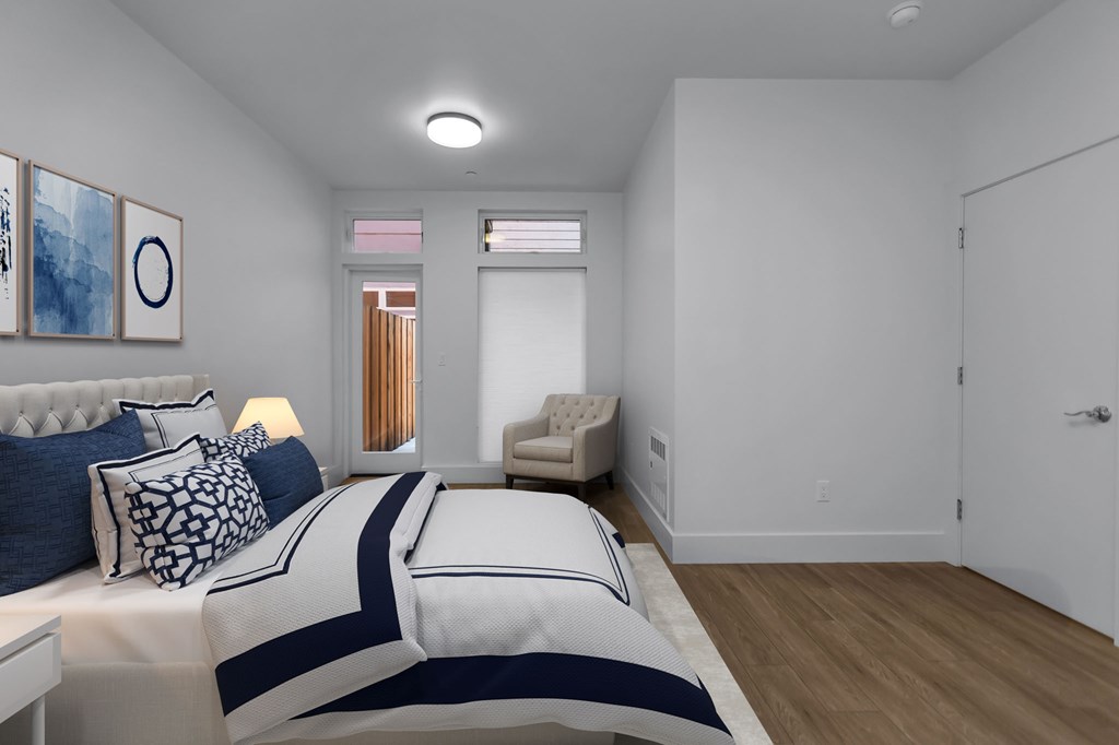 A bedroom with a bed, couch, and artwork on the wall.