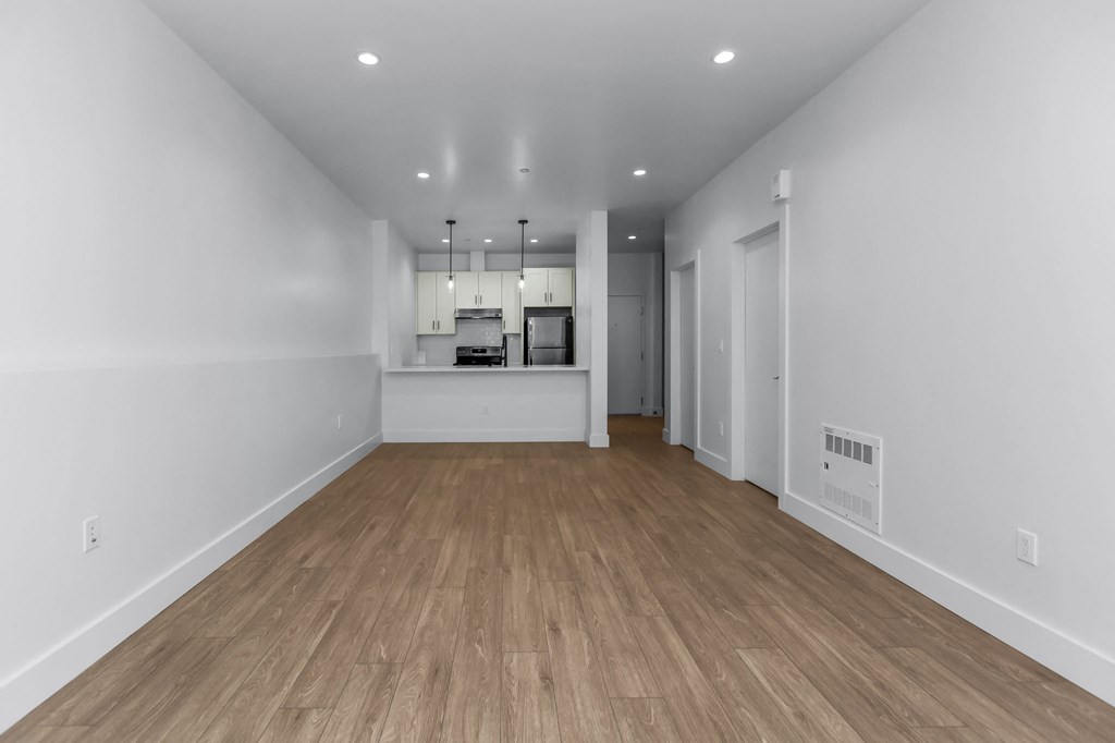 A long, empty hallway with wooden floors and white walls.