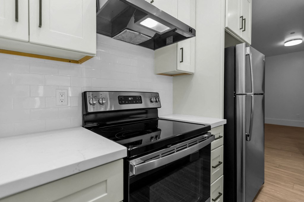 A modern kitchen with a black stove top oven and white cabinets.