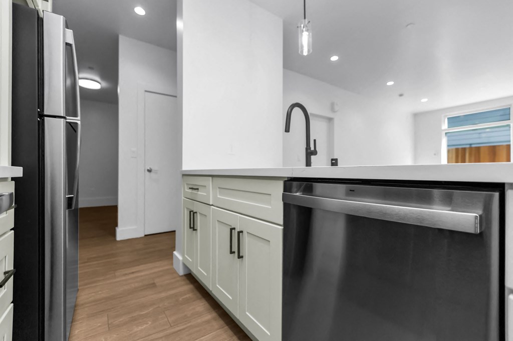 A modern kitchen with a stainless steel dishwasher and wooden floors.