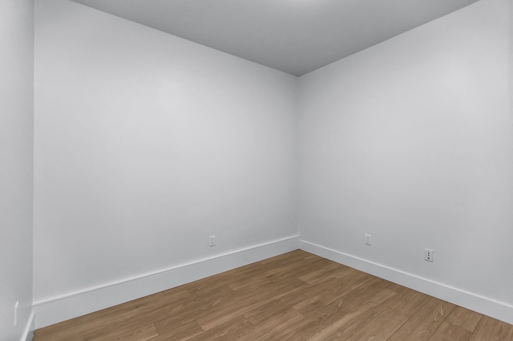 Empty room with wooden flooring and white walls.