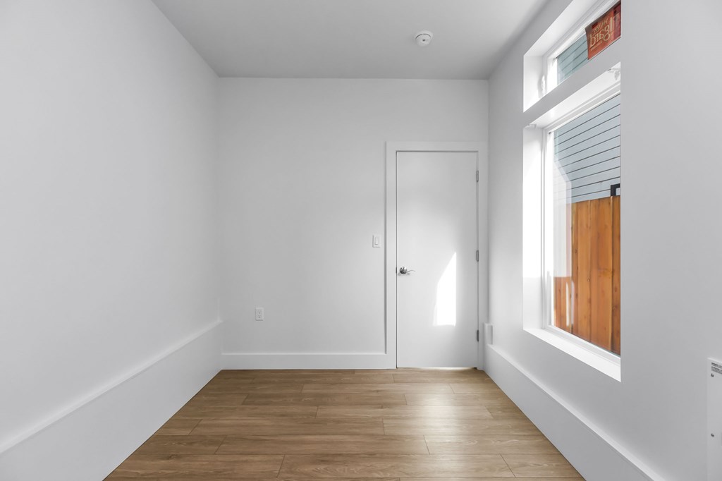 A room with a white door and a window with blinds.