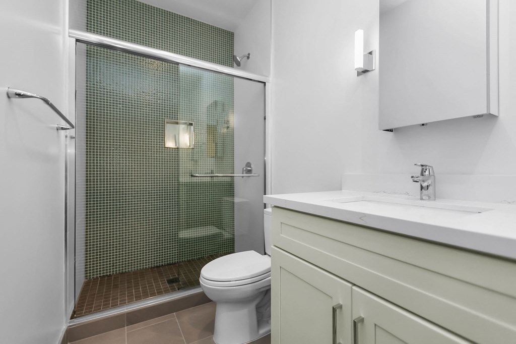 A white toilet sits in a bathroom with a glass shower door.