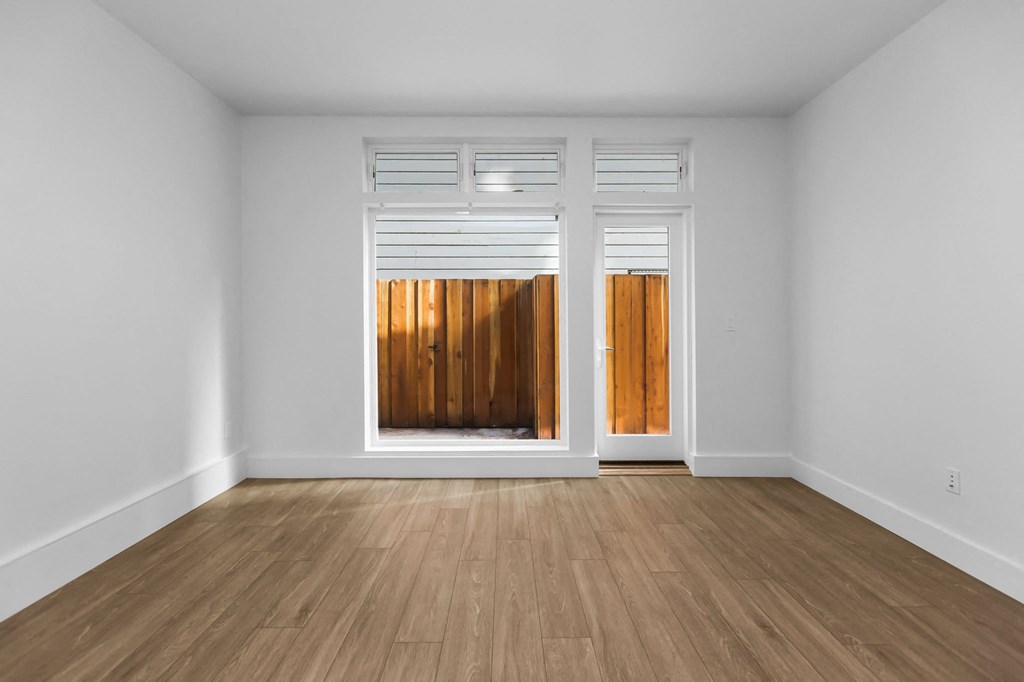 A room with a white wall and a wooden floor with a door.