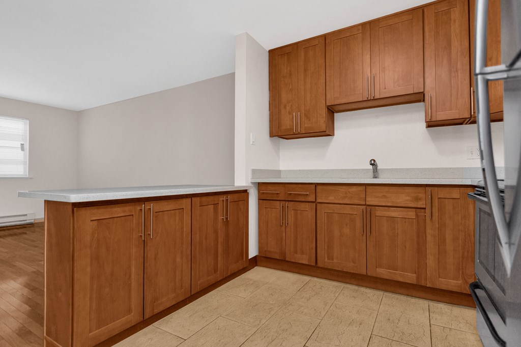 an empty kitchen with wooden cabinets and a refrigerator