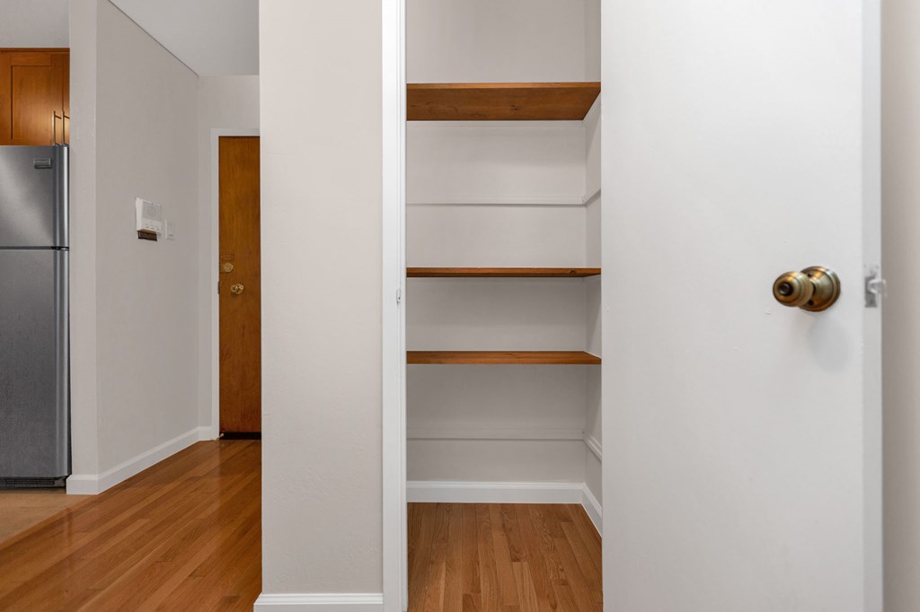 a room with white walls and shelves and a refrigerator