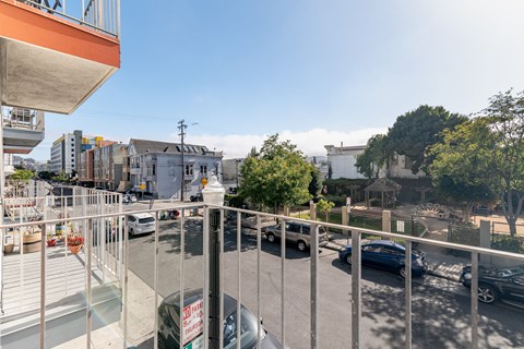 A view from a balcony overlooking a street with cars and buildings.