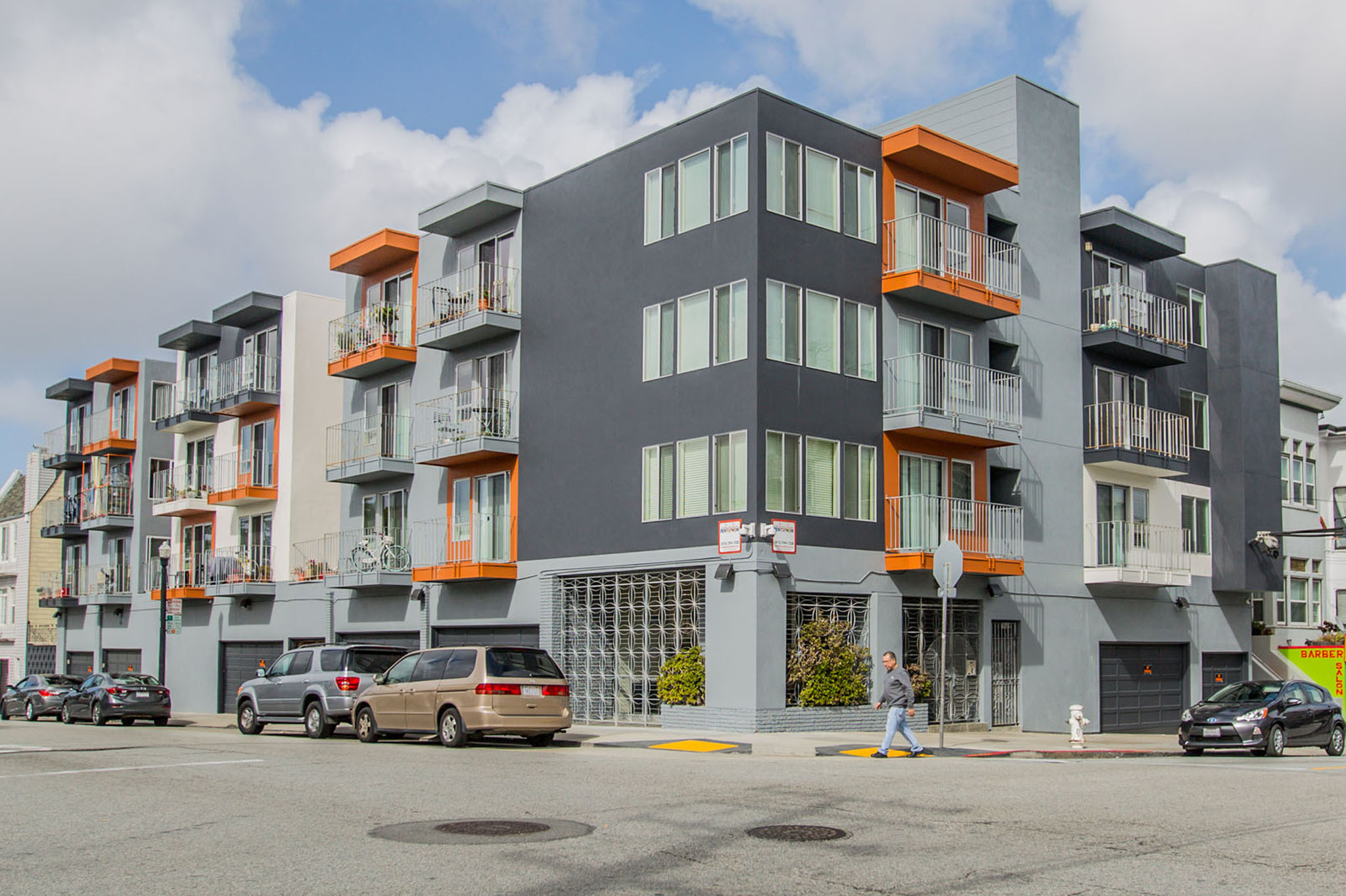 A modern apartment building with orange accents on the balconies.