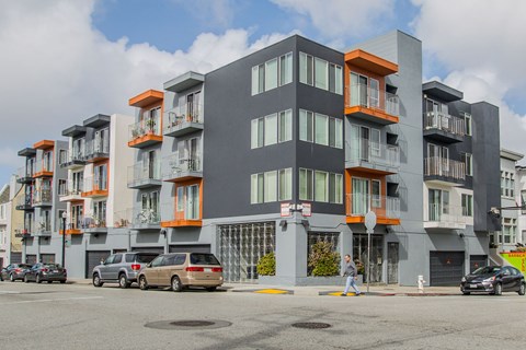 A modern apartment building with orange accents on the balconies.