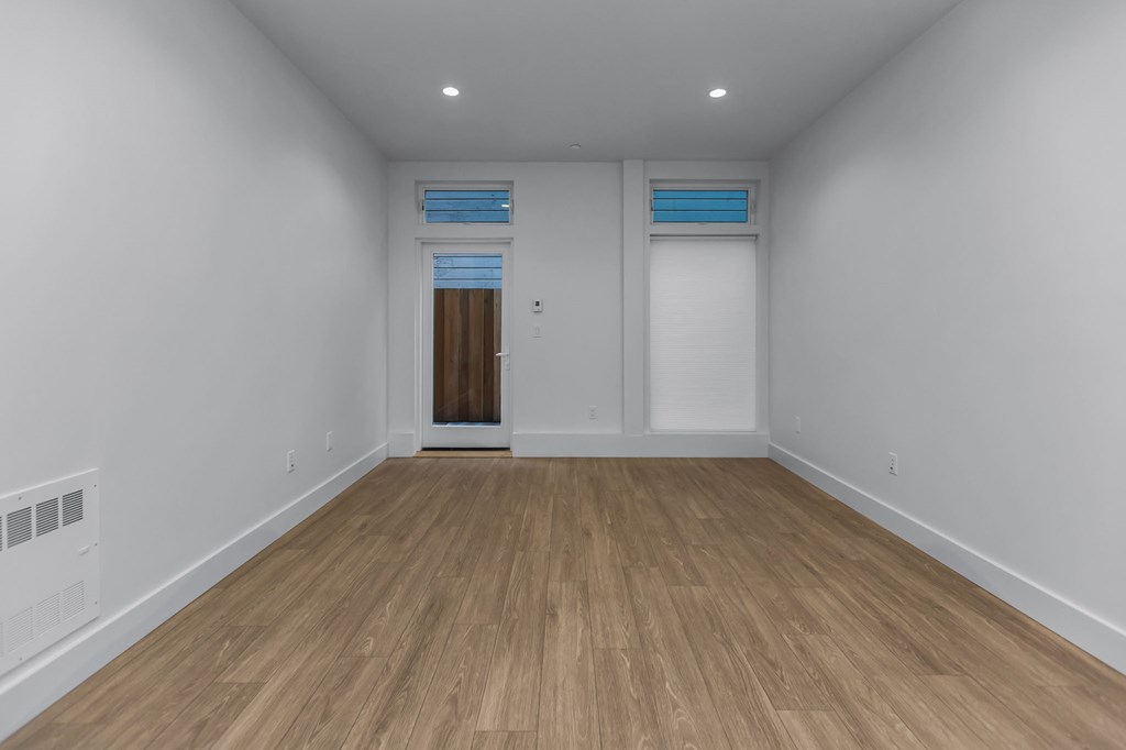 A room with wooden flooring and white walls.