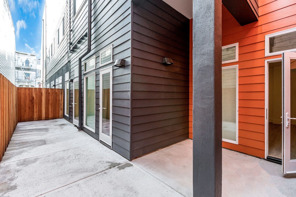 A patio area with a wooden fence and sliding glass doors.