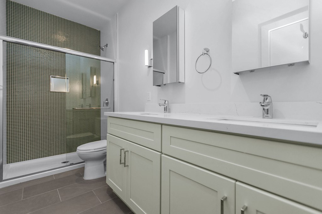 A bathroom with a toilet, sink, and mirror.