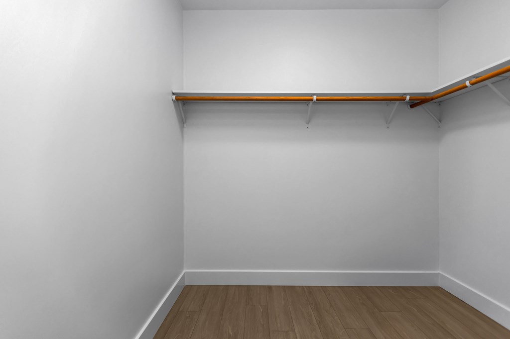 A white room with a wooden floor and a shelf on the wall.