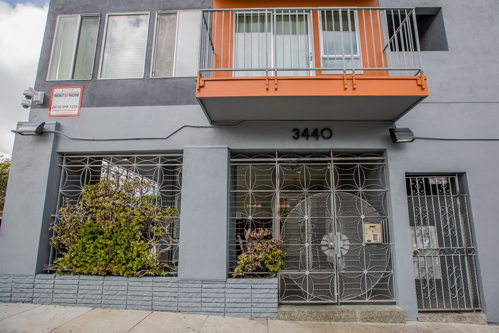 A grey building with a red sign on the left and a balcony on the right.