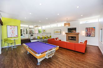 Recreation Room The recreation room is large with seating areas. A pool table and a large rectangular orange fabric sofa facing a fireplace with a TV.