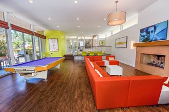 Recreation Room The recreation room is large with seating areas. A pool table and a large rectangular orange fabric sofa facing a fireplace with a TV.