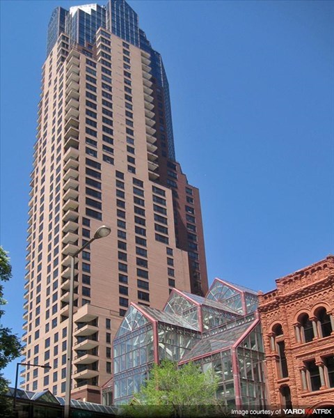 A tall building with a glass facade stands next to a smaller brick building.