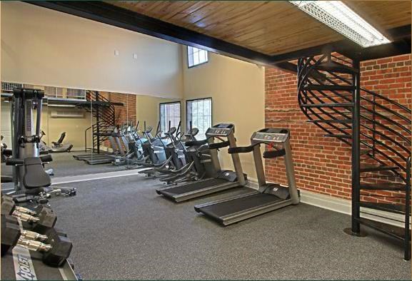 a gym with cardio equipment and a spiral staircase