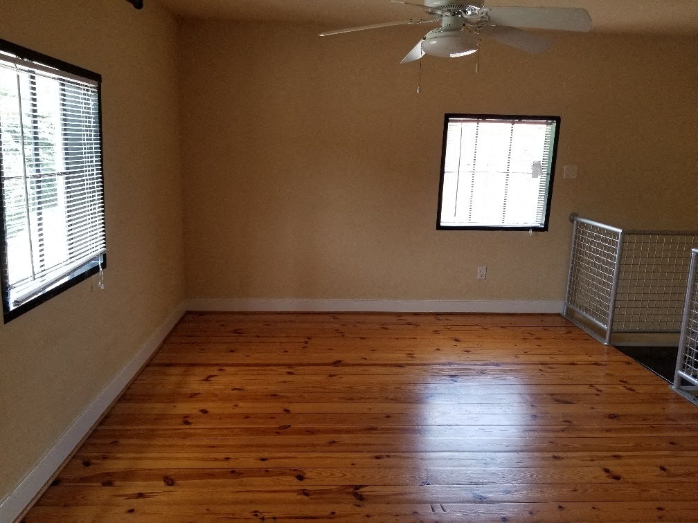 an empty living room with wooden floors and a ceiling fan