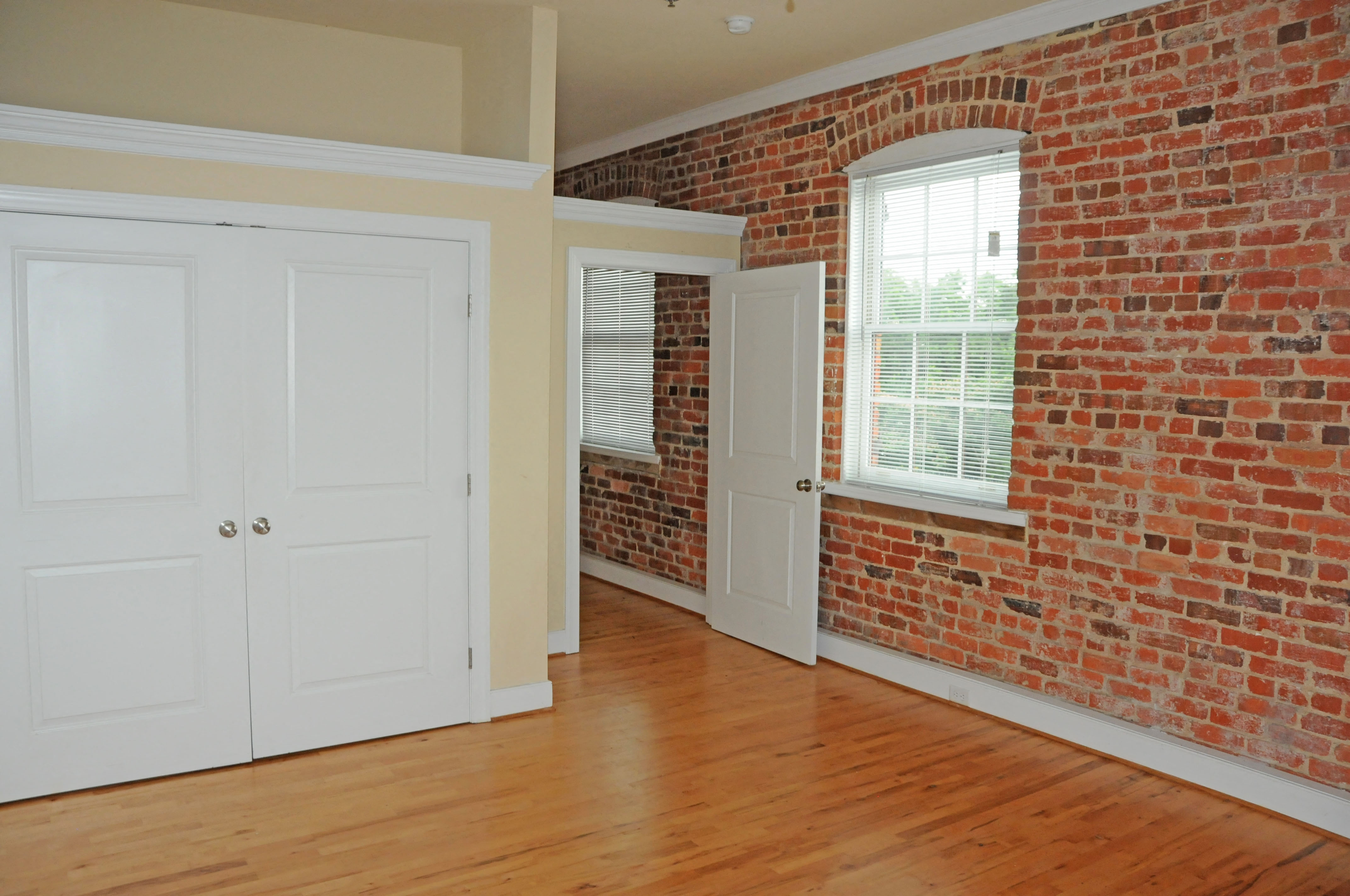 an exposed brick wall in a room with wooden floors and white doors
