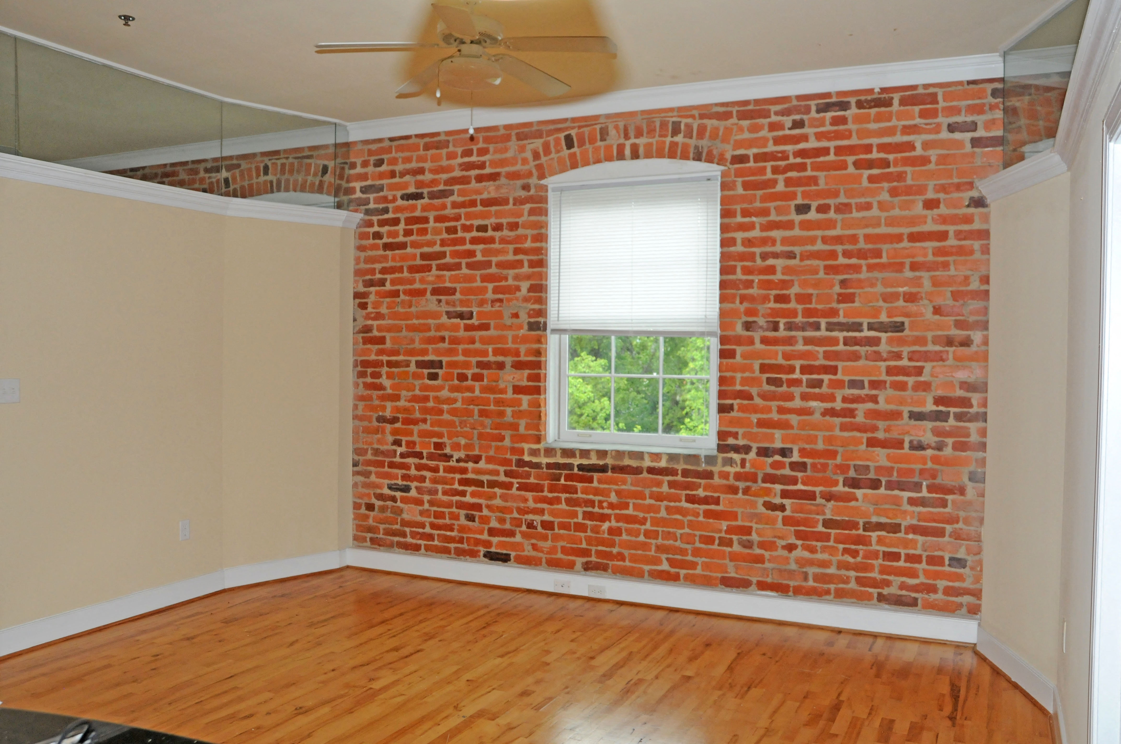 an empty room with a brick wall and a window
