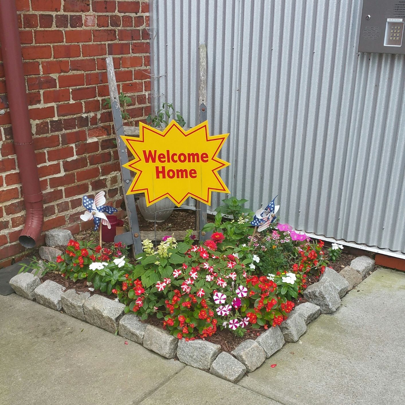 a sign that says welcome home in a flower garden
