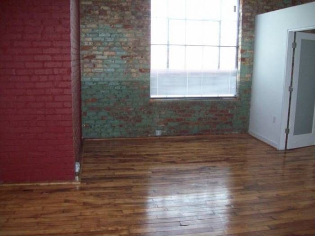 an empty room with a window and wooden floors