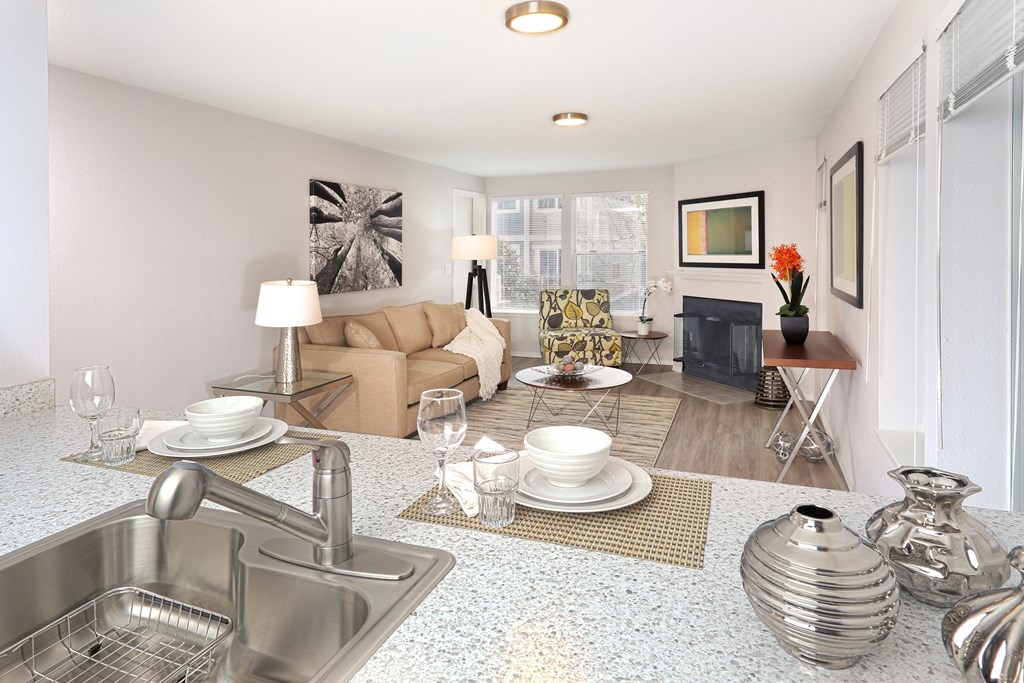 A modern kitchen with a stainless steel sink and a dining area with a couch and chairs.