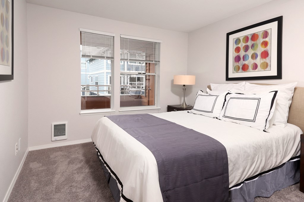 A bedroom with a large bed and a window overlooking a balcony.