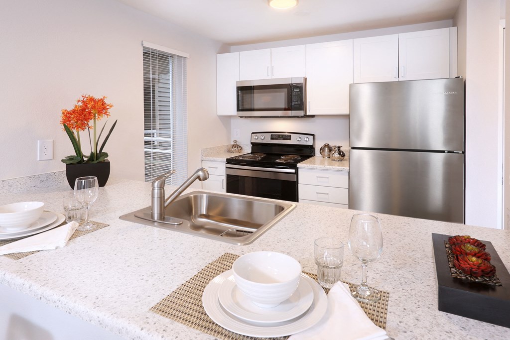 A modern kitchen with a stainless steel refrigerator and a white countertop.