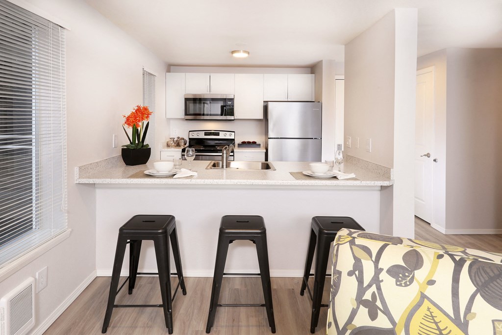 A kitchen with a white countertop and a fridge.