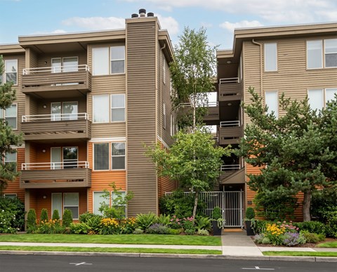 A brown apartment building with a gate in front.