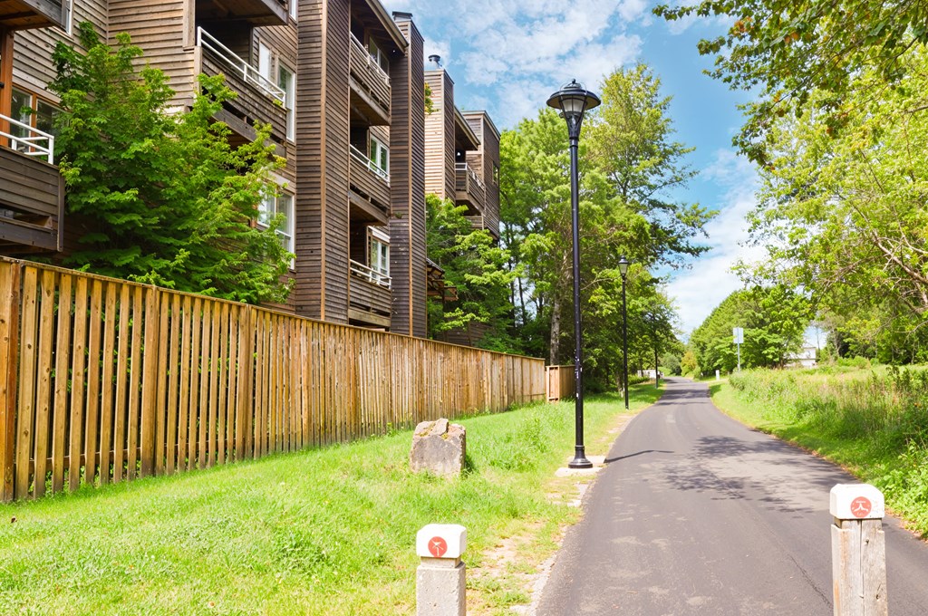 A street with a wooden fence and apartment buildings on the side.