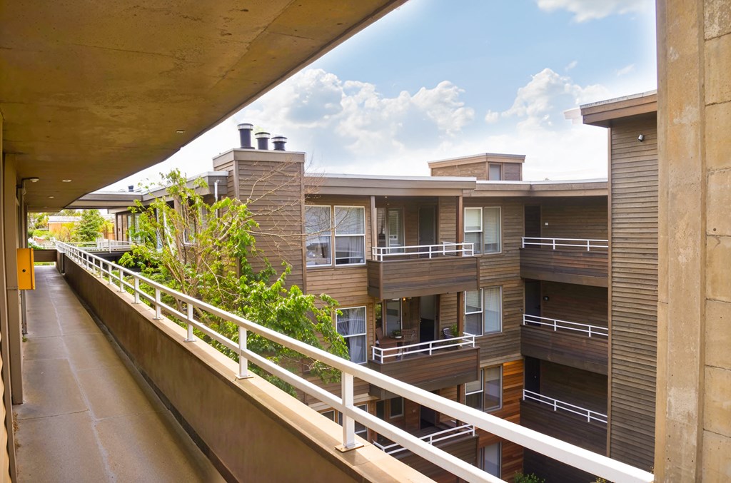 A balcony with a white railing and a building in the background.
