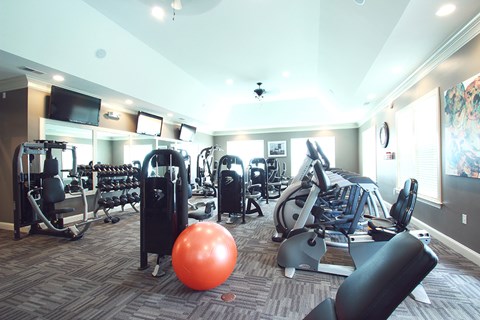 a gym with cardio machines and weights and a bowling ball