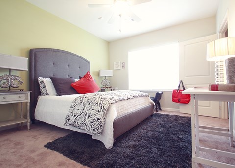 a bedroom with a bed and a desk and a window