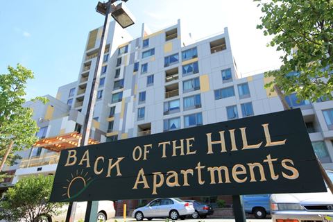 a sign for back of the hill apartments in front of a building