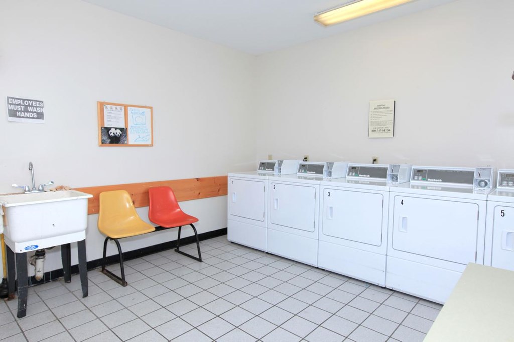 a washer and dryer room with a table and chairs and washing machines