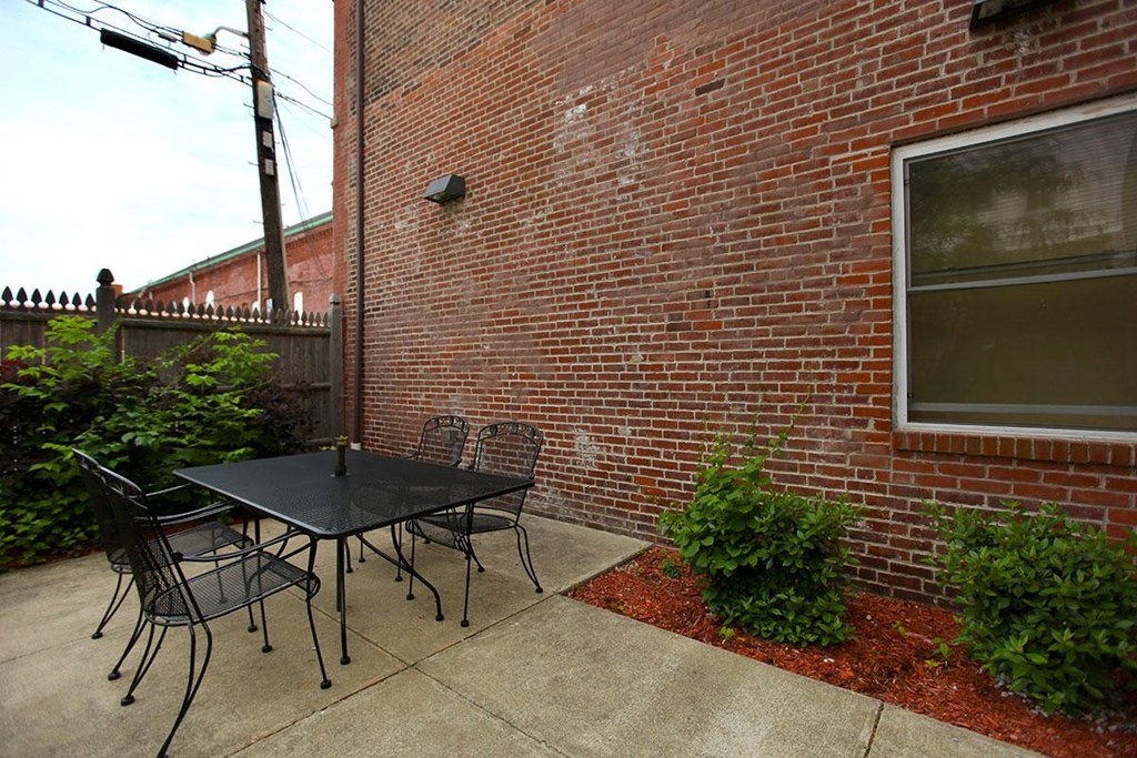 a patio with a table and chairs outside of a brick building