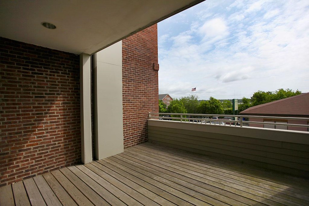 a balcony with a wooden deck and a brick wall