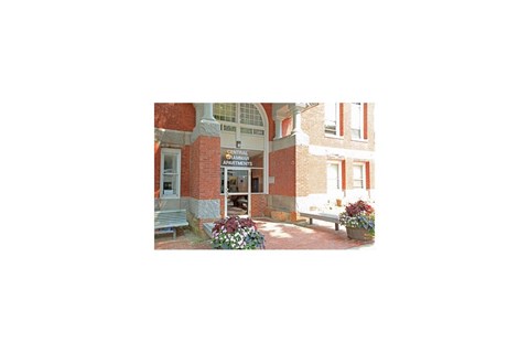 a view of the front of a building with flowers and a bench