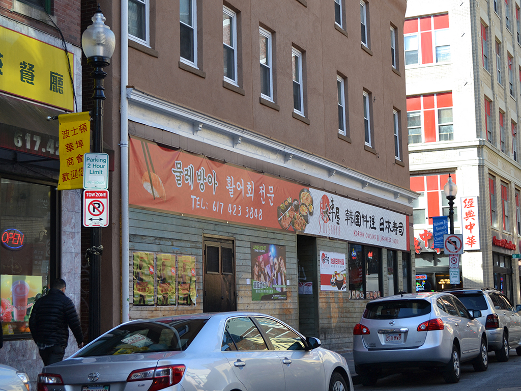 a busy city street with cars parked in front of a restaurant