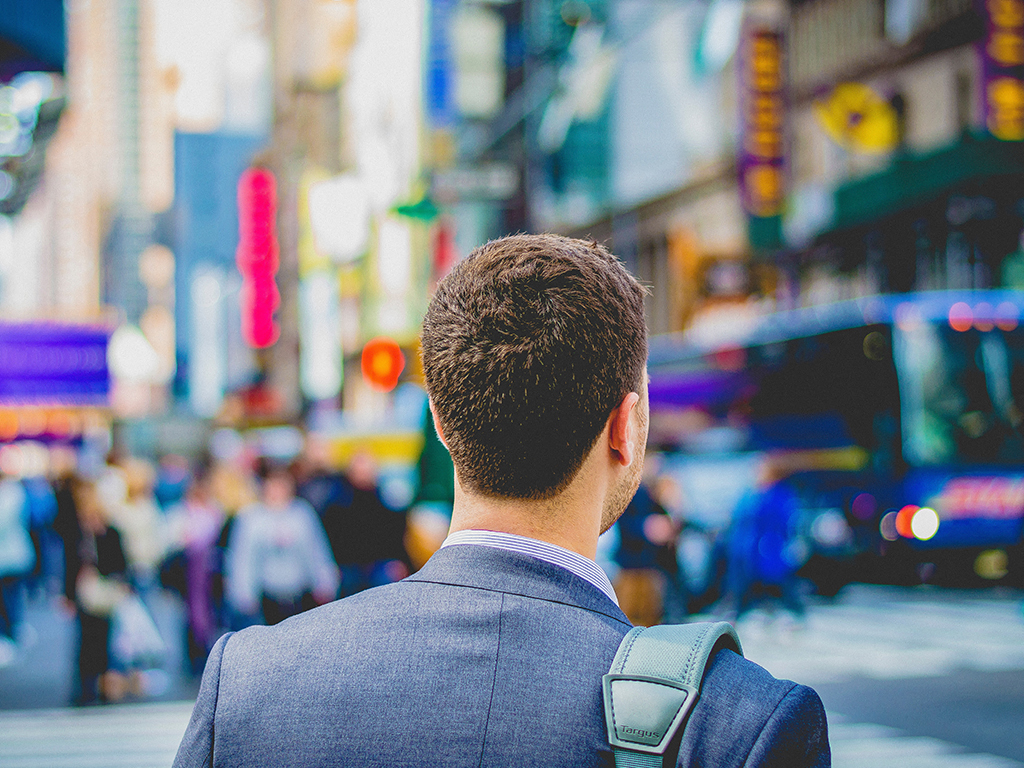 a man in a suit walking down a busy city street