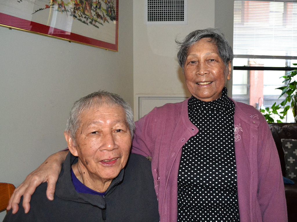 two older people posing for a picture in a living room