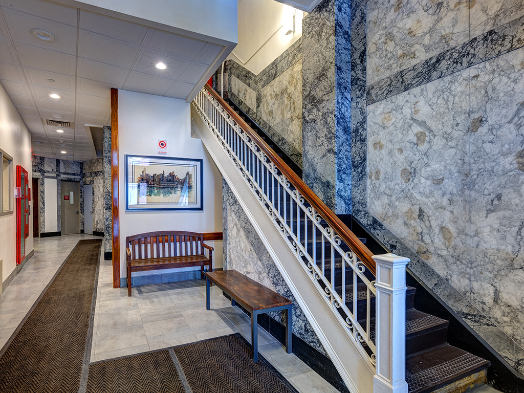 the lobby of a building with a staircase and a bench